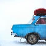 blue sedan with chain on tire parking on snowfield at daytime